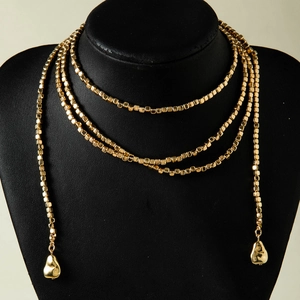 Primer plano de collar dorado de varias capas con cuentas y colgantes de gotas irregulares