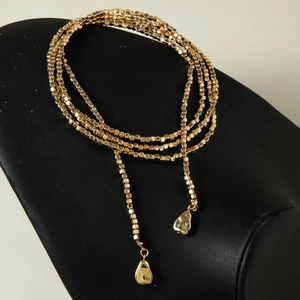 Detalle macro de collar de cuentas multicapa con acabado en oro de 18K y colgantes únicos