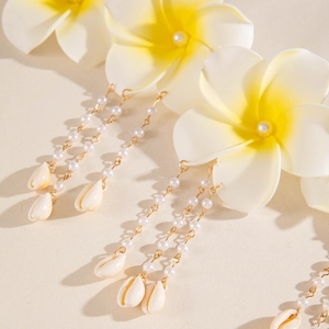 Détail d'une chaîne de perles multicouche avec fleurs de frangipanier et coquillages