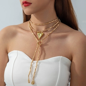 Detalle de collar de capas doradas con cadena de cuentas y colgante de corazón