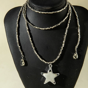 Detalle de collar plateado de cuentas con colgante de estrella y piezas de lágrima