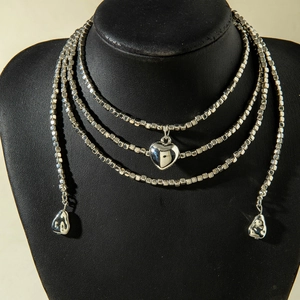 Detalle de collar de cuentas plateado de varias capas con colgantes metálicos