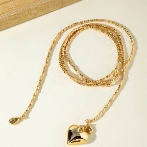 Detalle de collar de cuentas doradas en capas con un colgante de corazón pulido brillante