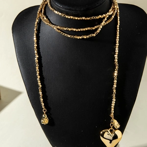 Detalle de collar de cuentas doradas de varias capas con colgante de corazón en busto