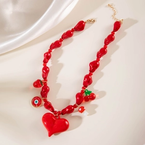 Détail du collier de perles rouges avec pendentif cœur et breloques cerise et œil
