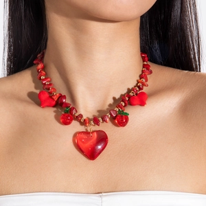 Gros plan détaillé des pendentifs cerise et cœur rouge sur un collier de pierres