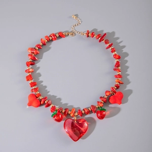 Détail d'un collier de perles rouges avec pendentifs cœur, breloques fraise et fermoir doré