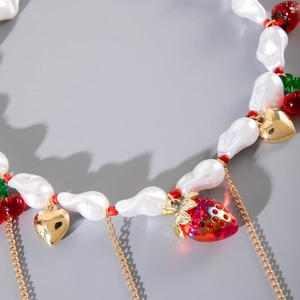 Dettaglio di perle barocche con pendenti a fragola e cuori dorati sulla collana di moda