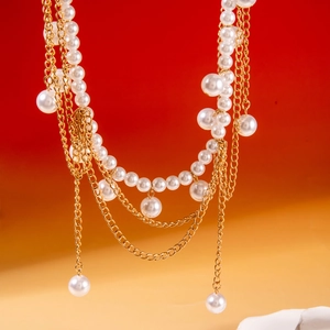 Détail d'une chaîne de taille dorée multicouche avec perles sur fond rouge vif