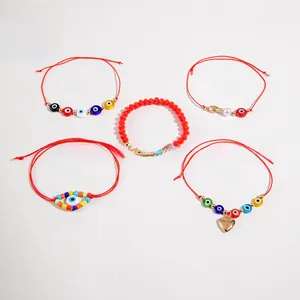 Detail of red Evil Eye beaded bracelet set with golden heart charms and woven cords