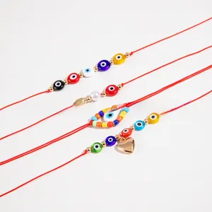 Detail of four handmade red string bracelets with evil eye beads and pearl charms