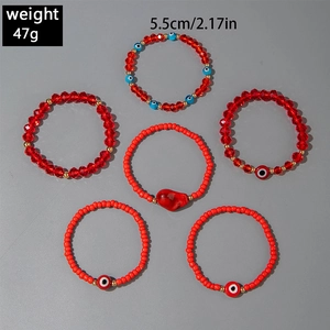 Detail of red Bohemian bead bracelet set with Evil Eye charms and irregular red stone pendant