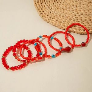 Detail of red beaded bohemian bracelets set with evil eye charms and a chili pendant