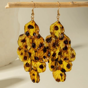 Detailed close-up of amber leopard print resin petal earrings on a wooden branch