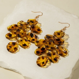 Detail of amber leopard print petal earrings on a stone display with golden hooks
