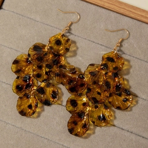 Macro detail of amber resin leopard print bow earrings on a grey velvet jewelry tray
