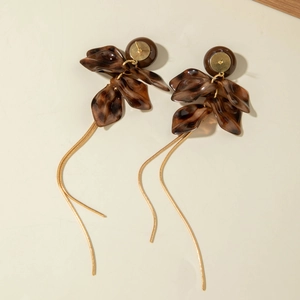 Detail of amber tortoiseshell resin flower earrings with long gold snake chain tassels