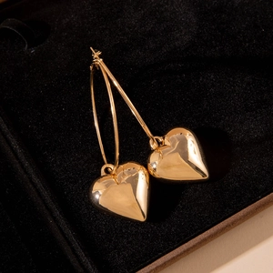 Elegant gold hollow heart pendant hoop earrings displayed on black velvet gift box