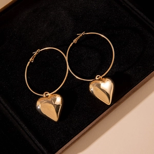 Polished gold hollow hoop earrings with thick heart pendants on black velvet background