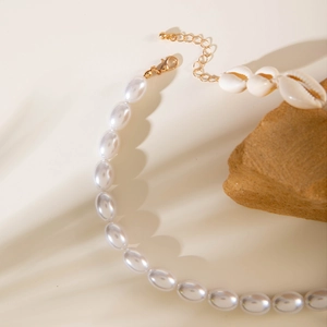 Baroque irregular pearl necklace with white shell pendant on natural rock background