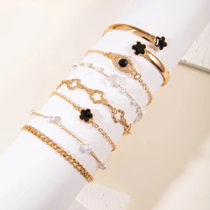 Golden bracelet set with evil eye charms, faux pearls, and clover motifs on white display
