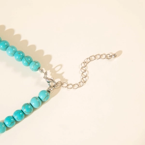 Détail des perles turquoise avec fermoir mousqueton argenté et chaîne d'extension du collier
