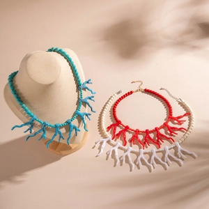 Vue détaillée de colliers de corail en acrylique turquoise, rouge et crème sur support