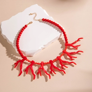Gros plan d'un collier de perles en acrylique corail rouge avec pendentifs sur pierre blanche