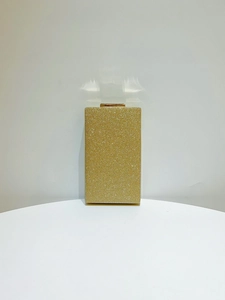Détail de la texture à paillettes et du fermoir doré sur la pochette de soirée