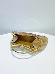 Close-up of champagne gold evening bag with colorful rhinestones and metal handle