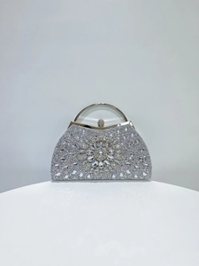 Detailed view of silver semicircular evening bag with crystal flower and rhinestones