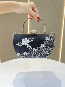Détail d'une pochette de soirée noire avec des strass brillants et des fleurs en perles