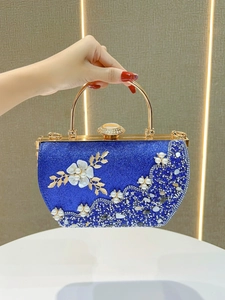 Gros plan d'une pochette de soirée bleu roi avec fleurs blanches et perles