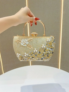 Détail du sac de soirée or champagne avec fleurs blanches et ornements de perles précieux
