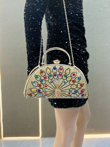 Detail view of peacock-shaped clutch bag with multicolor rhinestones and gold handle