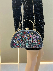 Macro shot of a peacock-patterned evening bag with colorful rhinestones and gold handle