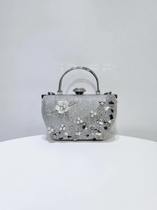 Gros plan d'un sac de soirée pailleté argenté avec fleurs 3D, perles et pierres précieuses