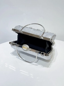 Détail du sac de soirée argenté à paillettes avec fermoir fleur perlée et anses rondes