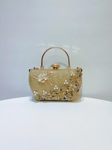 Détail du sac de soirée doré avec fleur 3D en métal et décorations élégantes en perles