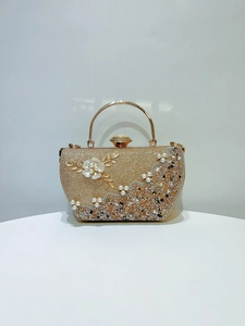Détail d'une pochette dorée ornée de perles, de strass et d'ornements floraux en métal