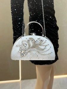 Detailed view of rhinestone evening clutch with silver handle and metallic chain strap