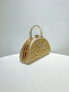 Detail of golden evening clutch bag with sparkling rhinestones and floral pattern