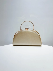 Detail of elegant gold evening bag with rhinestone clasp and circular metal handle