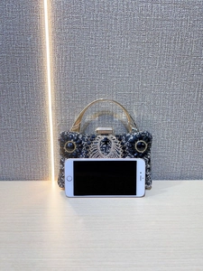 Detailed close-up of crystal encrusted evening clutch with golden handle on wooden surface