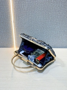 Detail view of the black sequined evening bag interior with luxury items to show capacity