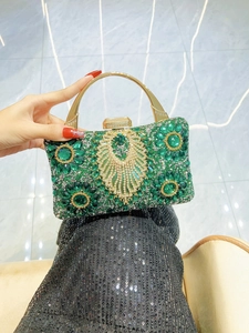 Detail of evening bag with emerald green crystals and gold peacock motif handle