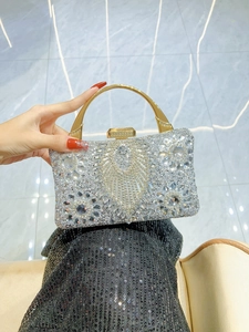 Detail of evening clutch featuring intricate crystal floral patterns and golden ring handle