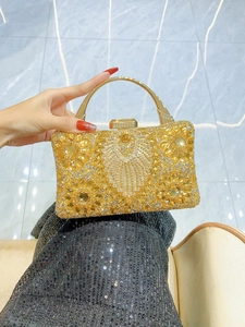 Detail of gold evening clutch bag with sparkling diamond-studded sunburst pattern and metal handle