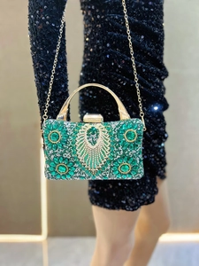 Close-up of emerald green crystal evening bag with intricate peacock and floral patterns