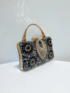 Detail of luxury black evening clutch featuring floral gemstones and rhinestone tassels